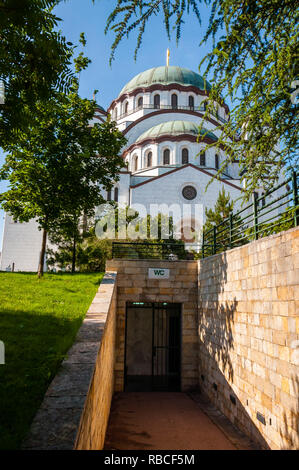 Belgrade, Serbia - June 09, 2013: Famous Saint Sava church exterior facade architecture surrounded by vibrant green spruce trees and entrance to publi Stock Photo