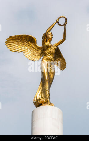 Skopje, Macedonia - June 10, 2013: Golden winged goddess woman holding wreath is a top part of the monument Fallen Heroes of Macedonia, located in the Stock Photo