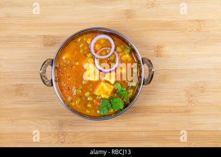 Indian Food or Indian Curry or Kadai Paneer in a copper brass serving bowl lying on wooden surface Stock Photo