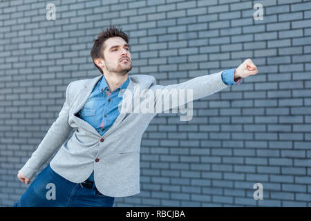 Profile side view portrait of serious handsome bearded man in casual style standing in superman gesture with fist and looking far. indoor studio shot  Stock Photo