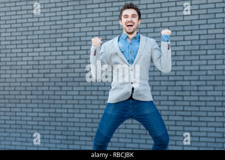 Portrait of excited happy handsome bearded man in casual style standing, jumping and looking at camera with happiness and celebrating his victory. ind Stock Photo