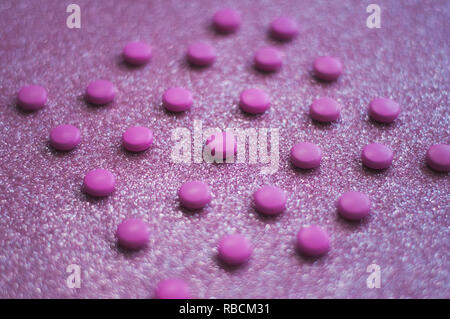 Pink pills, medicine isolated on glittery pink background. Stock Photo