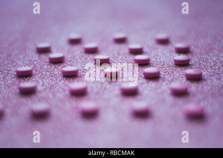 Pink pills, medicine isolated on glittery pink background. Stock Photo