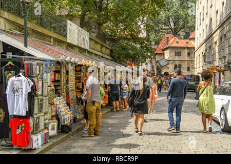 PRAGUE, CZECH REPUBLIC - JULY 2018: People browsing stalls selling souvenir goods on a side street in Prague city centre. Stock Photo