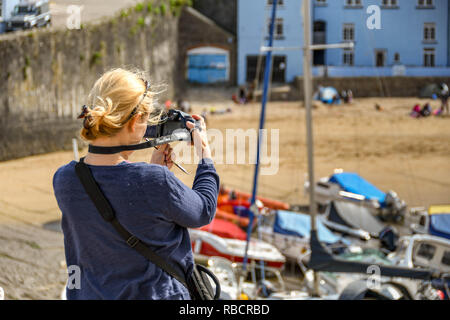 TENBY, PEMBROKESHIRE, WALES - AUGUST 2018: Person taking a photograph of the harbour in Tenby, West Wales, at low tide. Stock Photo