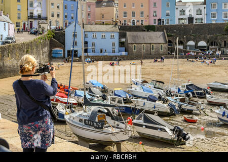 TENBY, PEMBROKESHIRE, WALES - AUGUST 2018: Person taking a photograph of the harbour in Tenby, West Wales, at low tide. Stock Photo