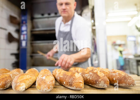 Dachsbach, Germany. 09th Jan, 2019. Arnd Erbel, master baker and confectioner and owner of the family bakery of the same name, lays baguettes from the oven on a baking board in the bakery of the company. Founded in the 17th century, the bakery has made a name for itself in the USA with bread, pretzels and gingerbread. Credit: Daniel Karmann/dpa/Ģ����ý Live News Stock Photo