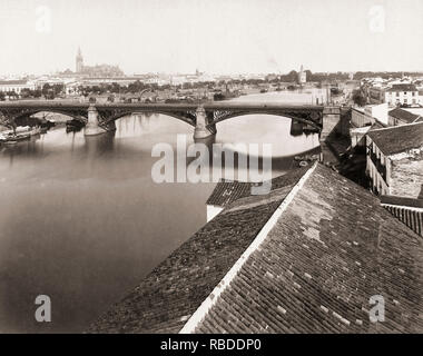Seville, Seville Province, Andalusia, Spain circa 1880. The Guadalquivir River.  In the mid-distance is the Triana Bridge.  The Cathedral with the Giralda Tower can be seen in the background, left, and the Torre de Oro, or Tower of Gold, to the right.  From a 19th century photograph. Stock Photo