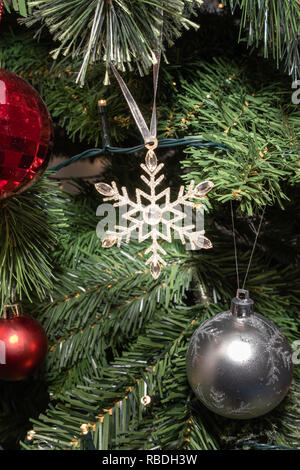 A glittery Christmas Star on a tree surroiunded by bobbles and Christmas lights. Stock Photo