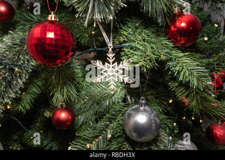 A glittery Christmas Star on a tree surroiunded by bobbles and Christmas lights. Stock Photo