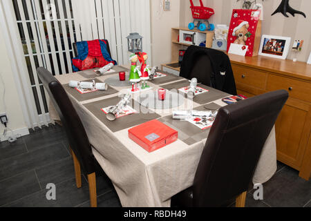 A simple family Christmas table with crackers and decorations  and in the process of being prepared for Christmas Lunch Stock Photo
