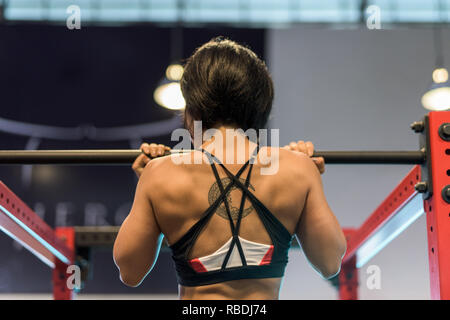 Rear view of a young muscular woman doing pull-ups on a horizontal