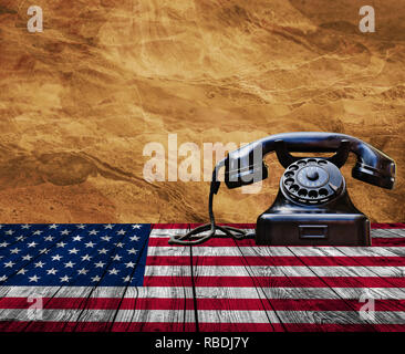 Old black phone on wooden table with Uneted states of America flag and yellow stone background Stock Photo