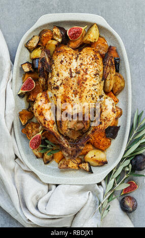 Baked turkey or juicy chicken with golden crispy skin with grapes and potatoes, tangerine. Roasted chicken in baking dish. Christmas dinner. Flat lay. Top view Stock Photo