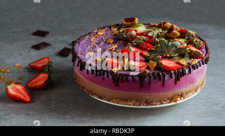 Vegan raw cake with strawberry and kiwi, cashew cream, coconut butter and coconut milk, and base made of almonds, dates and dried apricots, oat flakes, lyophilisated berry, top view Stock Photo