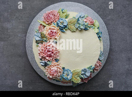 big wedding cake, decorated with buttercream flowers, on the grey stone background Stock Photo