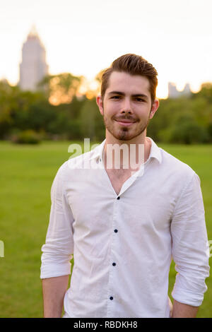 Portrait of young handsome man smiling in park Stock Photo