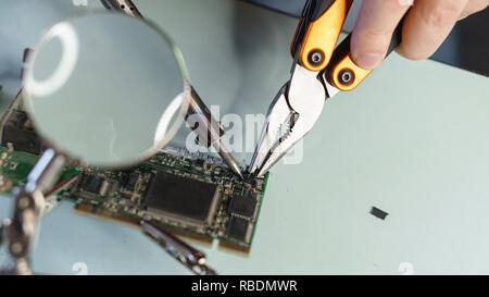 Repair motherboard. Service technician changes on-chip microcontroller. Troubleshooting. Man unrecognizable Stock Photo