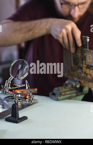 Repair motherboard. Service technician fixes chip in vice. Troubleshooting. Stock Photo
