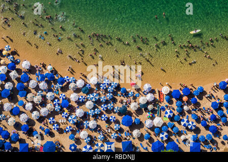 Salvador da Bahia, Brazil, aerial top view of umbrellas and people relaxing and bathing at Porto da Barra Beach in the summer. Stock Photo