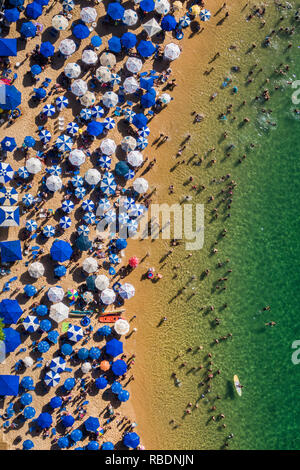 Salvador da Bahia, Brazil, aerial top view of umbrellas and people relaxing and bathing at Porto da Barra Beach in the summer. Stock Photo