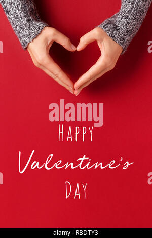 Female hands in shape of heart on red background with inscription Happy Valentine's day. Healthcare, love and chirty concept. Stock Photo