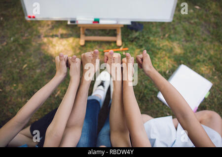 Children and teacher posing with raised hands Stock Photo