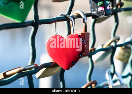 red heart-shaped lock hanging on a bridge in Zurich railing symbolizing everlasting love Stock Photo