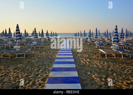 the beach is still deserted early in the morning with the umbrellas still closed Stock Photo