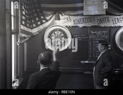 1950s, historical, lunchtime and working men in a pub playing a game of darts, England, UK. Stock Photo