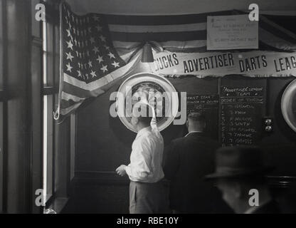 1950s, historical, lunchtime and working men in a pub playing a game of darts, England, UK. Stock Photo