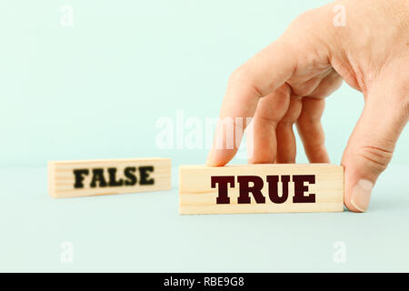 true or false concept man hand picking wooden cubes with text over wooden blue background Stock Photo
