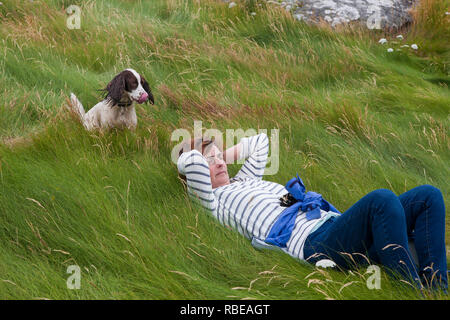 Dog waits to continue her walk while her mistress rests, Salakee Down, St. Mary's, Isles of Scilly, UK.  MODEL RELEASED Stock Photo