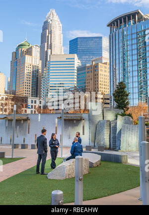 CHARLOTTE, NC, USA-1/8/19:  Four people, 3 men and one woman, stand in grassy area of Bearden park and socialize. Stock Photo