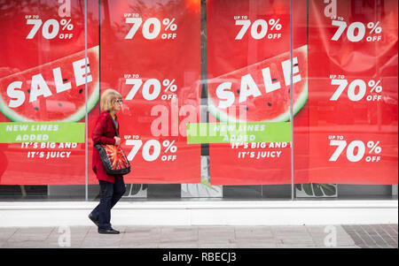 Woman walking past sale sign in New Look store window on Stockton high street. Stockton on Tees, north east England. UK Stock Photo