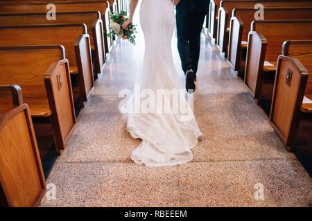 bride and groom walking down church aisle after ceremony Stock Photo
