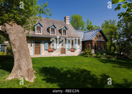 Old circa 1740 fieldstone cottage style home facade with new extension in spring. Stock Photo