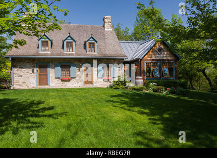 Old circa 1740 fieldstone cottage style home facade with new extension in spring. Stock Photo