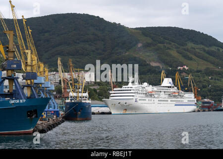 Summer view of Commercial Seaport of Petropavlovsk-Kamchatsky City on shore of Pacific Ocean - fishing ship and cruise liner at pier Stock Photo