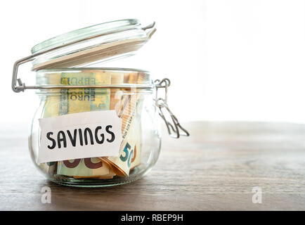 paper money in jar on wooden table Stock Photo