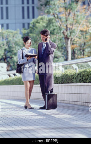 Japan. Tokyo. Man and woman executives standing outdoors in the city. Stock Photo