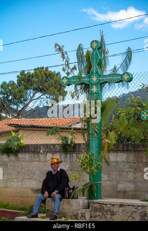 Mexican man wearing a traditional black sheep fur clothing beside green cross, San Juan Chamula, Chiapas, Mexico. Stock Photo