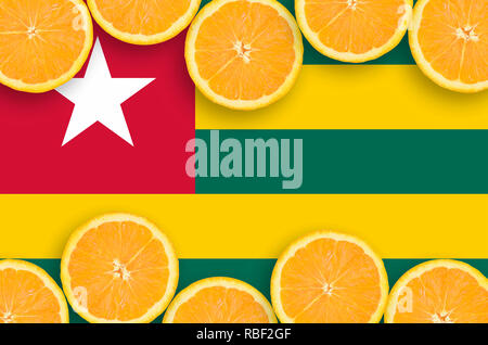 Togo flag  in horizontal frame of orange citrus fruit slices. Concept of growing as well as import and export of citrus fruits Stock Photo