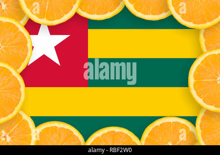 Togo flag  in frame of orange citrus fruit slices. Concept of growing as well as import and export of citrus fruits Stock Photo