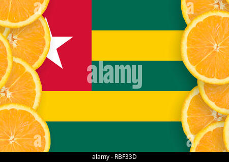 Togo flag  in vertical frame of orange citrus fruit slices. Concept of growing as well as import and export of citrus fruits Stock Photo