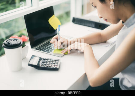 Young business woman hands with pen writing on note paper at home or office Stock Photo