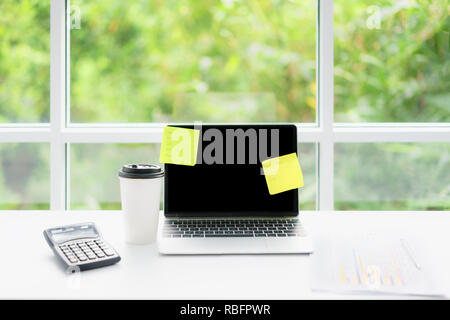 Blank screen laptop computer and coffee cup on table at coffee cafe with nature in background. Technology, business and modern life concept Stock Photo