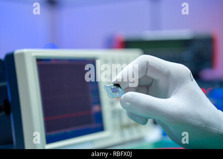 Hand with small electronic microchip microcontroller Stock Photo