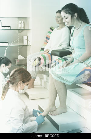 Female friends enjoying and relaxing at beauty spa while getting pedicure Stock Photo
