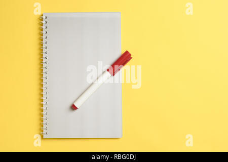 Top view of white paper blank notepad with marker on yellow paper background. Color of year 2019 Top view or flat lay. Copy space for text. Vertical. Stock Photo
